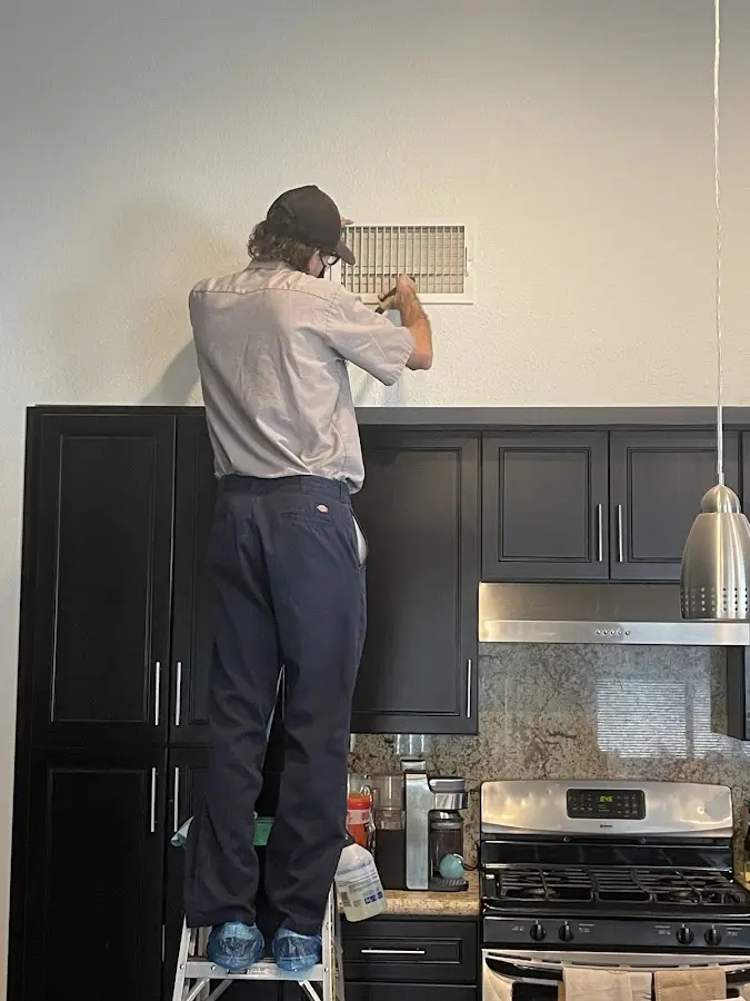 Technician inspecting an air vent during HVAC service in Bear Creek